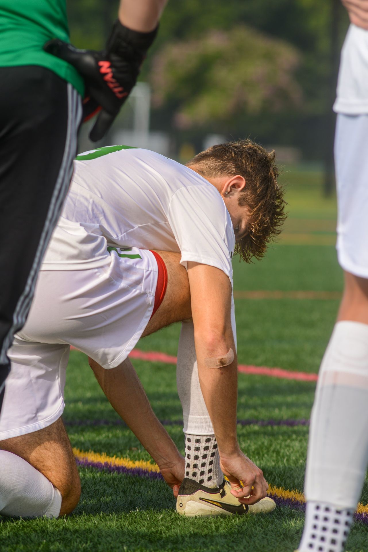 Aidyn Smith tying his right cleat during warm-up talk